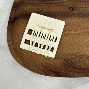 Vue détaillée de trois barrettes à cheveux crème sur une carte de présentation pro