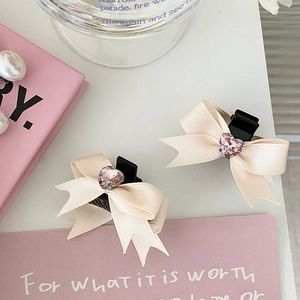 Détail des barrettes nœuds en soie crème avec cristal en forme de cœur rose