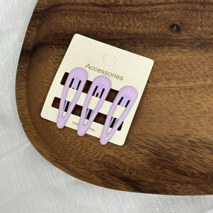 Détail de trois pinces à cheveux BB violettes brillantes sur carte d'accessoires