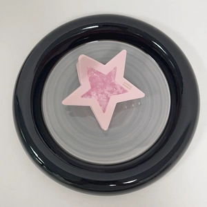 Pink star-shaped acetate hair claw clip with glitter filling on a ceramic plate