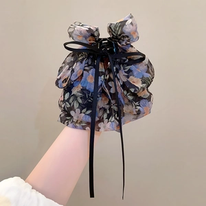 Vue détaillée d'une grande pince à cheveux en mousseline fleurie bleue avec nœud élégant