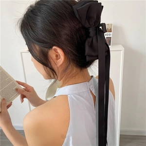 Détail d'une grande pince à cheveux avec nœud en ruban noir portée en queue de cheval