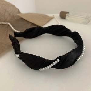 Close-up of black twisted satin headband decorated with white pearls on a vintage background