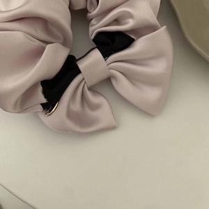 Haargummi aus Satin mit rosa und schwarzer Schleife und goldenem Anhänger auf weiß