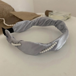 Detail of light gray satin headband with parallel white pearls and twisted fabric texture