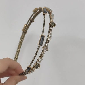 Detail of double-layer golden headband with dark grey crystals and clear rhinestones