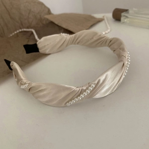 Detail of champagne satin twisted headband with pearl accents and black anti-slip tips