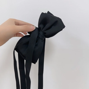 Détail d'une grande pince à cheveux en satin noir avec de longs rubans élégants