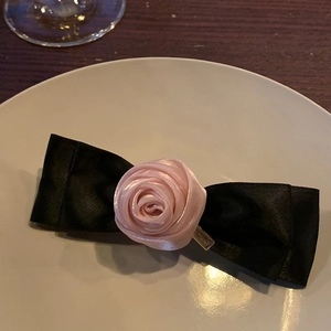 Detail of pink satin rose and black ribbon bow hair clip with gold metal base