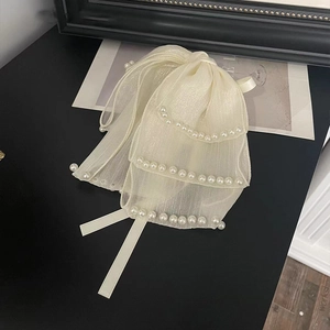Détail d'une pince à cheveux élégante en tulle beige avec perles blanches bordées