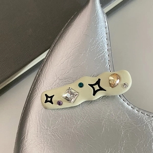 Vue macro d'une pince à cheveux Y2K crème avec strass colorés et étoiles noires