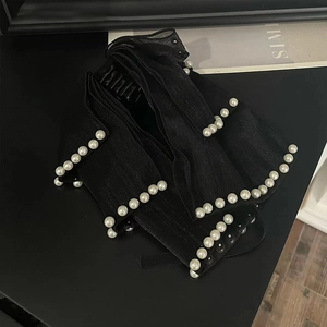 Détail de la pince à cheveux en satin noir avec perles doubles et nœud élégant
