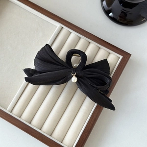 Détail d'une élégante pince à cheveux en satin noir avec un petit pendentif en perle