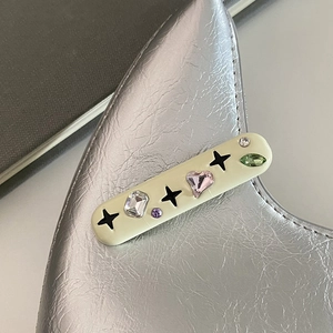 Vue macro d'une pince à cheveux étoile Y2K avec strass colorés sur un sac en cuir