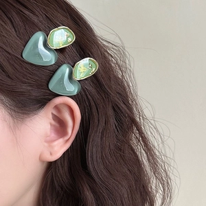 Close-up of heart-shaped green hair clips worn on wavy hair for a stylish look