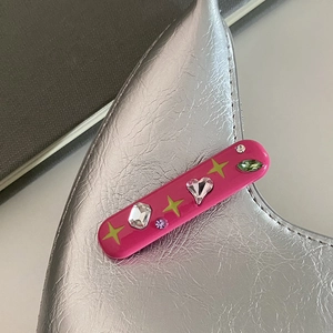 Gros plan sur une barrette étoile Y2K rose vif avec des étoiles néon et des strass colorés