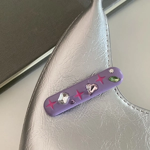 Vue détaillée d'une barrette violette aux couleurs acidulées avec strass brillants variés