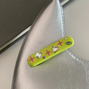 Détail de la pince à cheveux Y2K vert fluo avec strass colorés sur fond argenté brillant