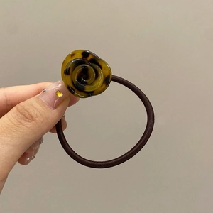 Detail shot of a resin rose hair tie with brown tortoise shell pattern held by hand