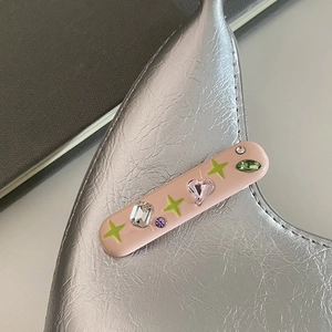 Gros plan d'une pince à cheveux rose avec des strass colorés et des motifs d'étoiles