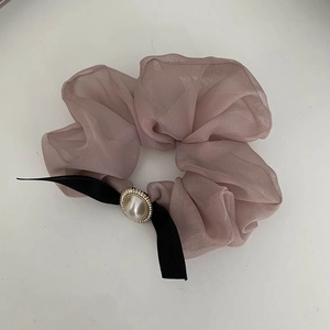 Détail d'un chouchou en organza lilas avec un nœud en satin noir et une perle