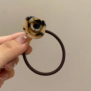 Close-up of a floral acrylic hair tie with a brown tortoiseshell rose pattern decoration