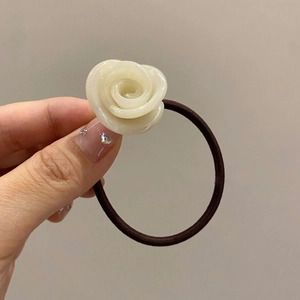 Close-up of a creamy white resin rose hair tie with a black high-elasticity band