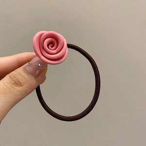 Close-up of a pink resin rose hair tie held in hand, showing glossy texture and petals