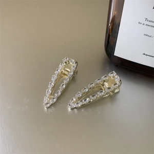 Detail view of two gold French vintage hair clips with sparkling drop-shaped zirconias
