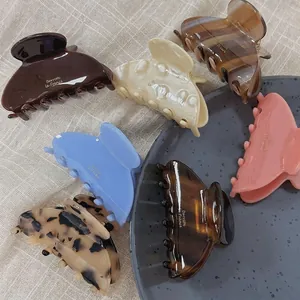 Set of seven aesthetic acetate hair claws in various colors and patterns on a tray