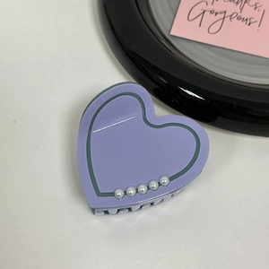 Detail of purple acetate heart hair claw with green outline and inlaid white pearls