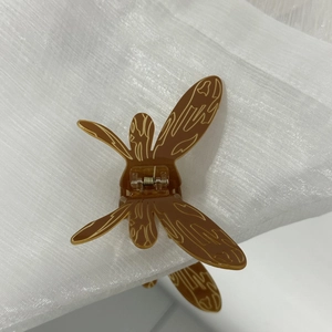 Pince à cheveux libellule avec texture ambre brun et motif bionique sur tissu blanc