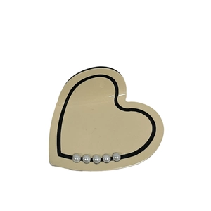 Elegant beige heart hair claw with black trim and five decorative pearls on white background