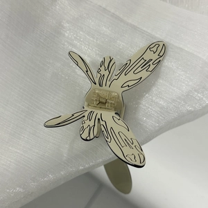Détail de la pince à cheveux papillon crème avec texture noire sur tissu plissé