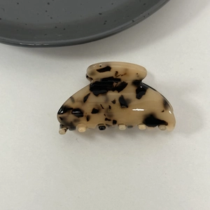 Macro detail of tortoiseshell acetate claw clip with golden lettering and glossy finish
