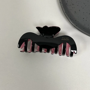 Close-up of black and pink acetate shark hair claw clip with gold brand lettering