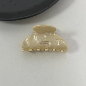 Detail view of cream acetate hair claw clip featuring Barrette la France logo engraving