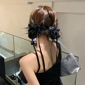 Barrette nœud en velours noir avec plumes portée sur un chignon élégant pour femme