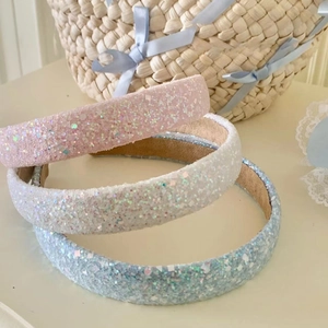 Détail de trois serre-têtes à paillettes rose, blanc et bleu avec doublure velours