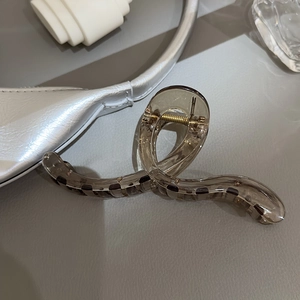 Détail macro d'une pince à cheveux ambre avec design torsadé et ressort métallique robuste