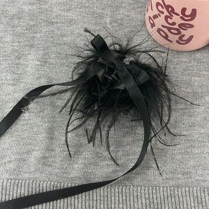 Détail de la pince à cheveux vintage avec plumes noires et ruban élégant