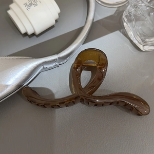 Détail d'une grande pince à cheveux ambre translucide au design torsadé et élégant