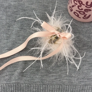 Gros plan d'une pince à cheveux avec plumes blanches et long ruban en soie rose