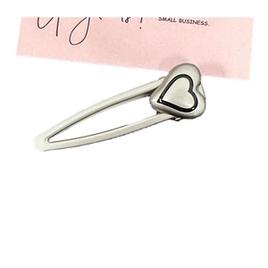 Fermaglio per capelli in metallo argento opaco con design a cuore su carta rosa