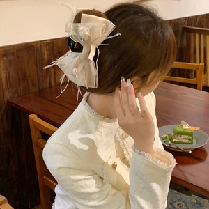 Pince à cheveux noeud crème élégante avec plumes sur un chignon sophistiqué