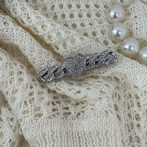Close-up of a silver heart-shaped hair clip with sparkling rhinestones on lace