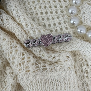 Detail of silver Y2K star hair clip with pink rhinestones on a woven cream background