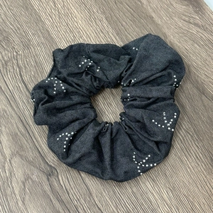 Detail of oversized dark grey denim scrunchie with white dot star patterns on wood