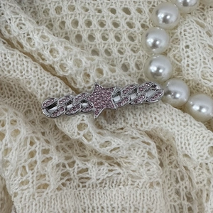 Close-up of Y2K silver star hair clip with pink rhinestones on lace background