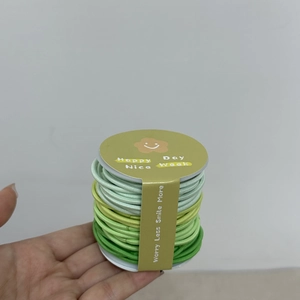 Gros plan d'élastiques à cheveux dégradés verts dans un emballage cadeau simple